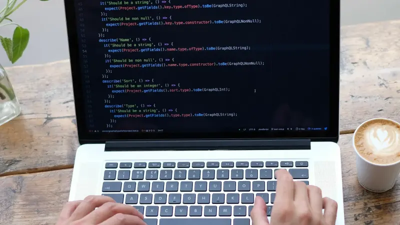 Person tippt Code auf einem Laptop-Bildschirm